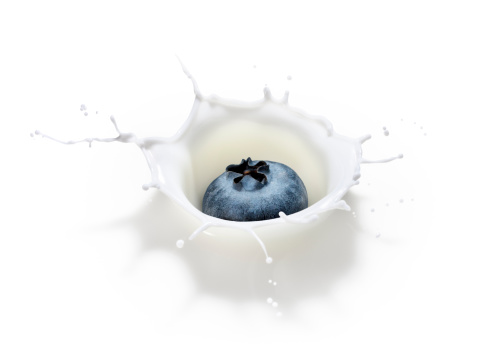 Perfect splash form a blueberry falling into milk.