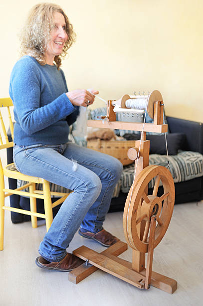 Woman at spinning wheel in home workshop. Loom in the background. Taken in Provence, France