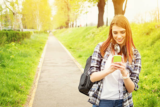 Capelli rossi ragazza scuola felice con smartphone SMS - foto stock