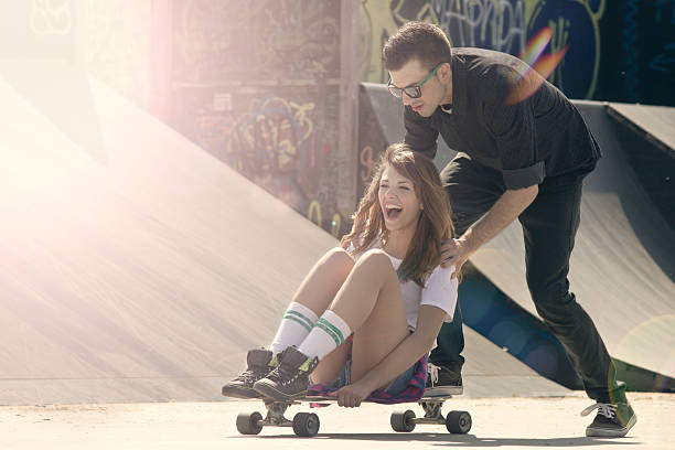 istock Man pushing woman sitting on skateboard 492866921
