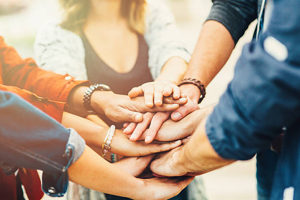 Teamwork A group of friends putting their hand one over another. hands clasped stock pictures, royalty-free photos & images