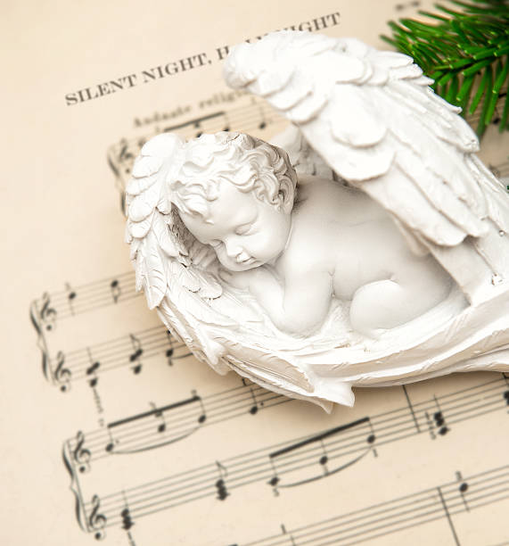 Little lovely sleeping angel with vintage style christmas decoration and music notes from ca. 1900 on background. Silent Night, Holy Night