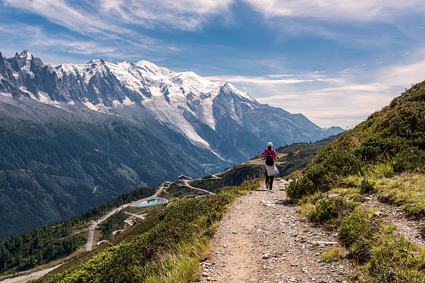 Young woman walking on a footpath in the mountains Young woman with the backpack walking on a footpath in the mountains. Sunny summer day with blue sky and clouds. France, Mont Blanc mont blanc photos stock pictures, royalty-free photos & images