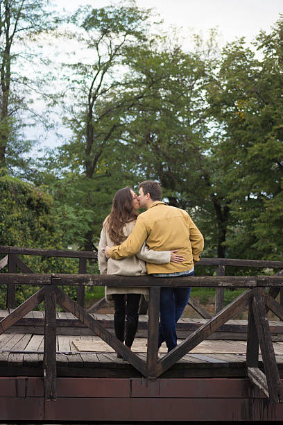 istock Young couple in 20s, leaning on wooden bridge. 492883020