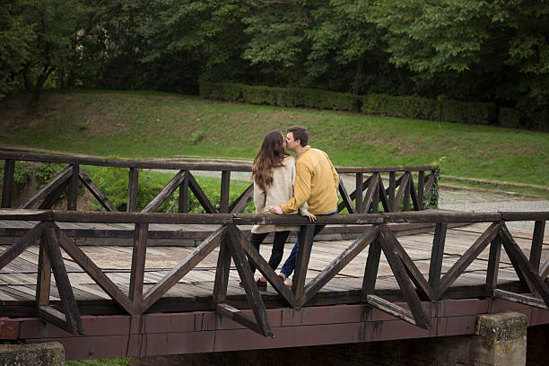 istock Young couple in 20s, leaning on wooden bridge. 492883084