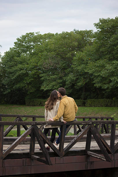 istock Young couple in 20s, leaning on wooden bridge. 492883176