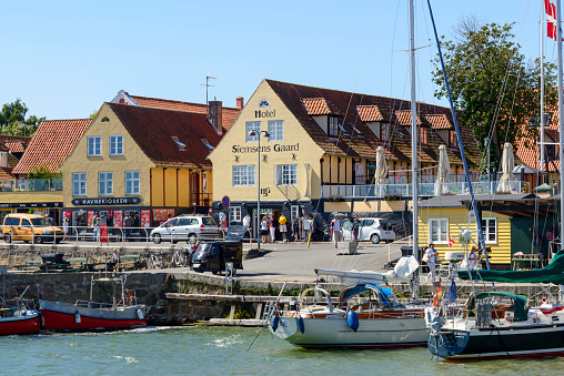 Svaneke, Denmark - August 14, 2015: Tourists enjoy the sunny weather and walking along the quay at the port.