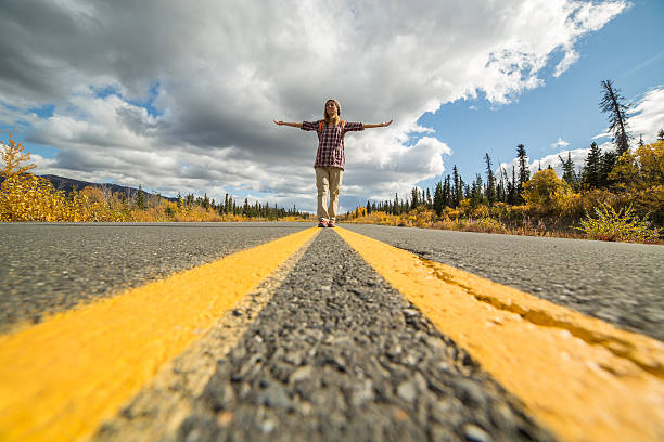istock Lone woman standing on road arms outstretched 492884782