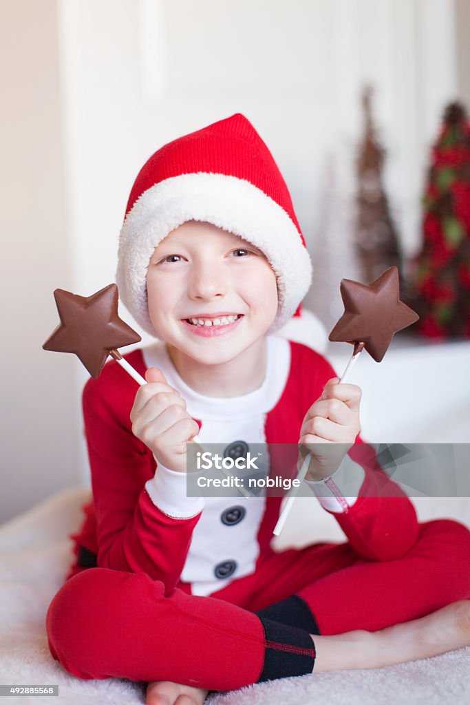 boy at christmas time cheerful little boy in elf costume holding star shaped chocolate candies and enjoying cozy christmas time at home 2015 Stock Photo