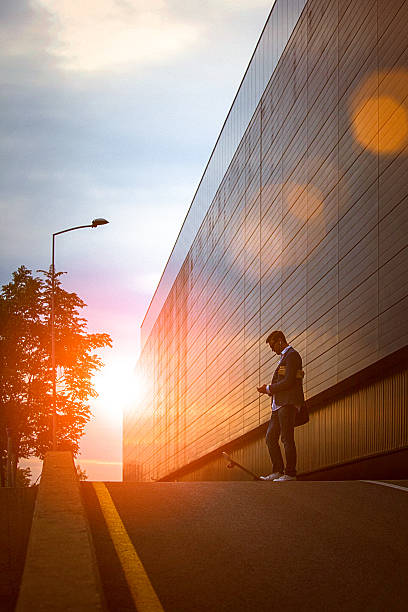 Young entrepreneur using smartphone in the urban environment at sunset stock photo