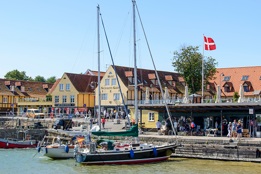 Svaneke, Denmark - August 14, 2015: Tourists enjoy the sunny weather and walking along the quay at the port.