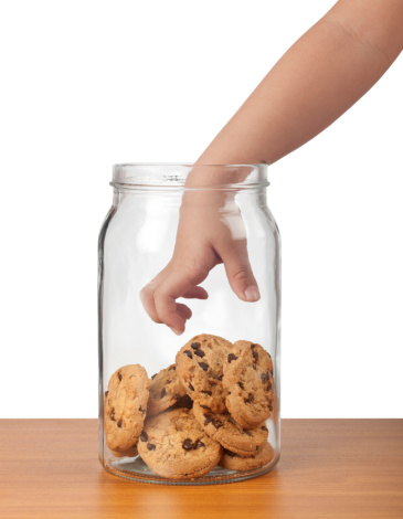 Child's hand reaching out to take cookies from a jar