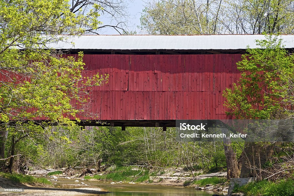 Covered Bridge Crossing Creek The red Wilkins Mill Covered Bridge spans Sugar Creek in rural Parke County, Indiana near Rockville. Rockville - Maryland Stock Photo