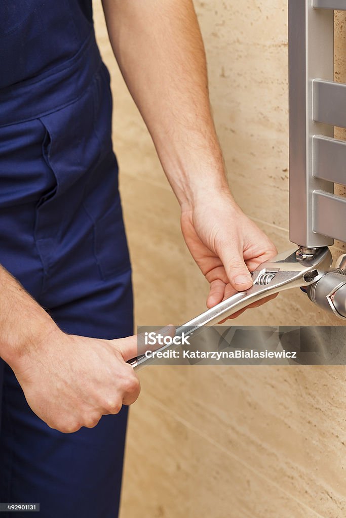 Repairing heater Handyman repairing heater with a metal wrench Adult Stock Photo