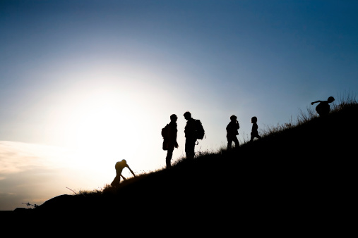 Silhouettes of parents with children rising uphill