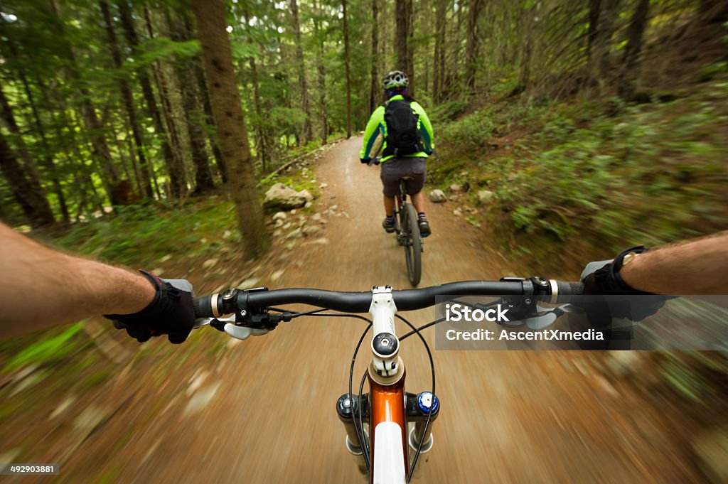 Follow me POV image of a mountain biker following another biker on a trail Mountain Biking Stock Photo