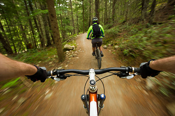 Follow me POV image of a mountain biker following another biker on a trail exhilaration photos stock pictures, royalty-free photos & images