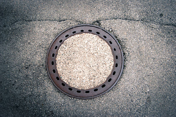 Old manhole cover Old manhole cover on asphald ground sewer lid stock pictures, royalty-free photos & images
