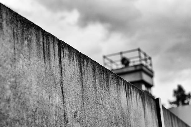 Berliner Mauer mit Wachturm / Berlin Wall and watchtower Perspective black / white photograph of the Berlin Wall. In the background a watchtower can be seen. cold war photos stock pictures, royalty-free photos & images