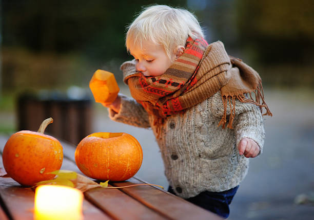 Toddler boy playing with halloween pumpkins, halloween party