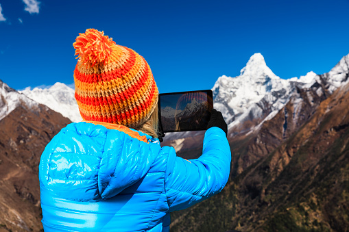Young woman taking picture of mount Ama Dablam in Himalayas. Woman, wearing blue jacket and orange cap, is holding a black tablet, mount Ama Dablam is on her right. Mount Everest National Park. This is the highest national park in the world, with the entire park located above 3,000 m ( 9,700 ft). This park includes three peaks higher than 8,000 m, including Mt Everest. Therefore, most of the park area is very rugged and steep, with its terrain cut by deep rivers and glaciers. Unlike other parks in the plain areas, this park can be divided into four climate zones because of the rising altitude. 