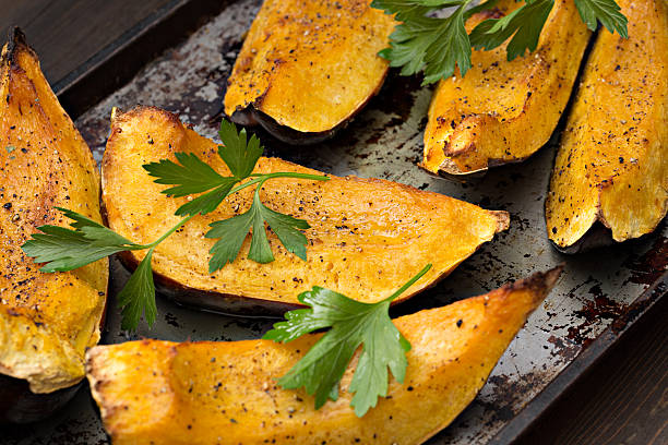 Baked Acorn Squash A high angle close up horizontal photograph of several pieces of baked acorn squash garnished with some fresh parsley. acorn squash stock pictures, royalty-free photos & images