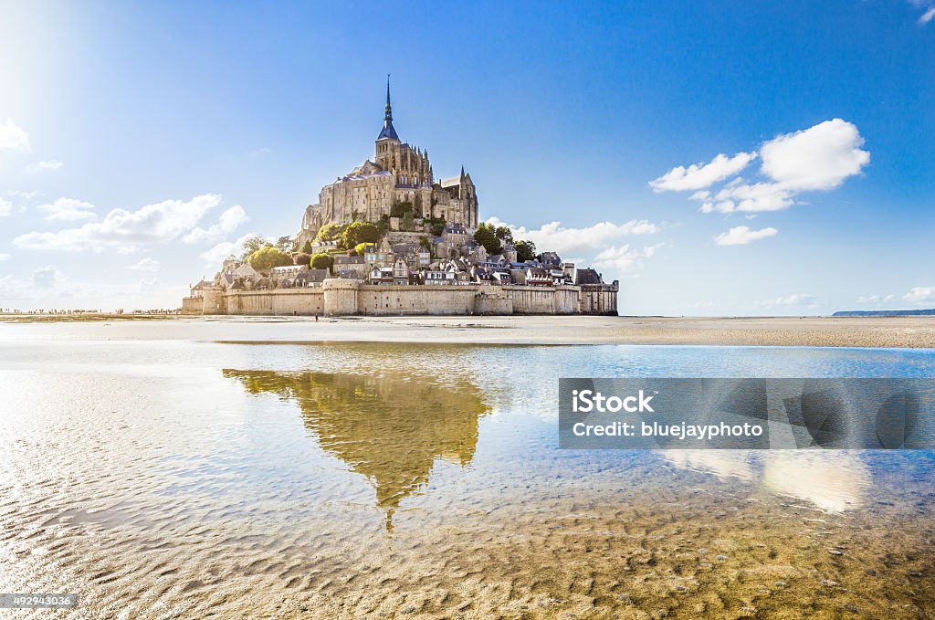 Mont Saint-Michel, Normandy, France Panoramic view of famous Le Mont Saint-Michel tidal island on a sunny day with blue sky and clouds, Normandy, northern France. Mont Saint-Michel Stock Photo