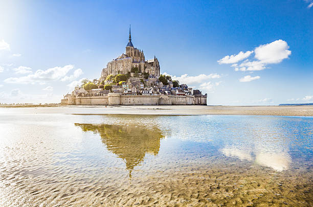 Mont Saint-Michel, Normandy, France Panoramic view of famous Le Mont Saint-Michel tidal island on a sunny day with blue sky and clouds, Normandy, northern France. tide photos stock pictures, royalty-free photos & images