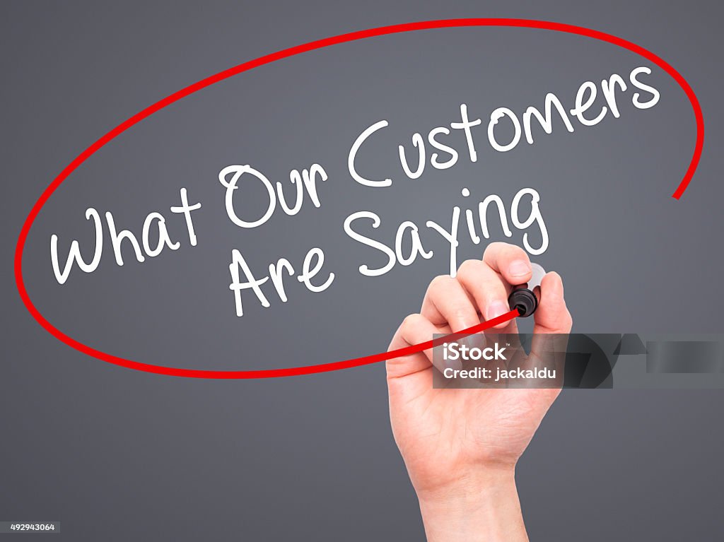 Man Hand writing What Our Customers Are Saying with marker Man Hand writing What Our Customers Are Saying with black marker on visual screen. Isolated on grey. Business, technology, internet concept. Stock Photo Customer Stock Photo