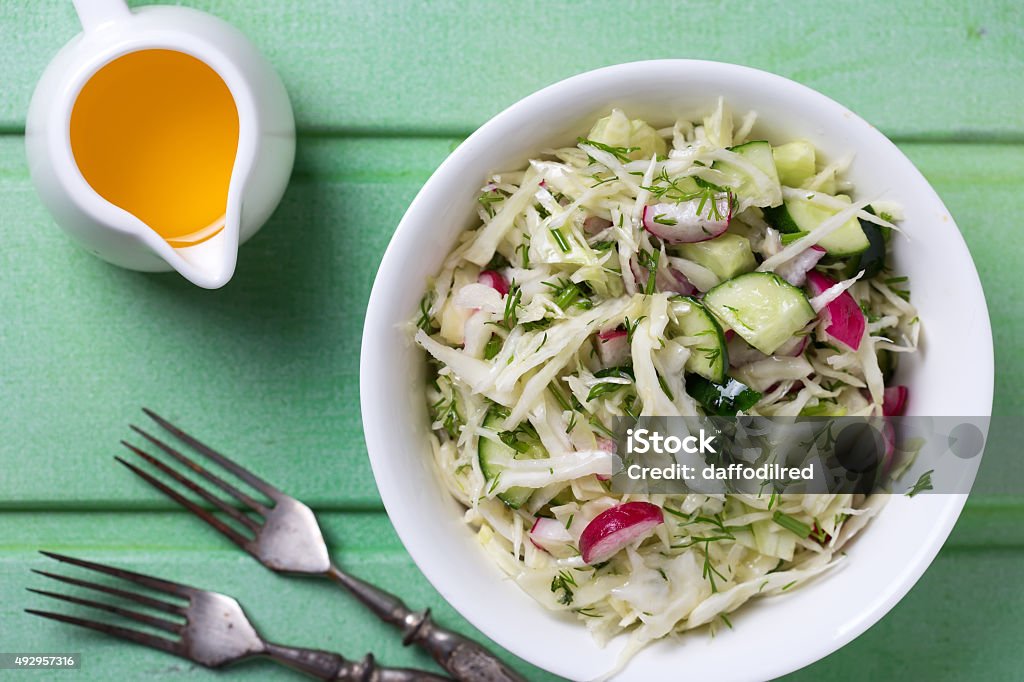Fresh salad Salad from cabbage, herbs, cucumber, onion and radish in bowl on green wooden background. Coleslaw. Selective focus. 2015 Stock Photo