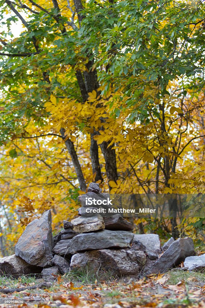 Cairn rock pile in woods - Autumn A pile of rocks (cairn) taken at the summit of blodgett hill at the Merrimck New Hampshire Horse Hill Nature Preserve. This photo was taken in the fall and showcases some deep orange and yellow foliage. 2015 Stock Photo