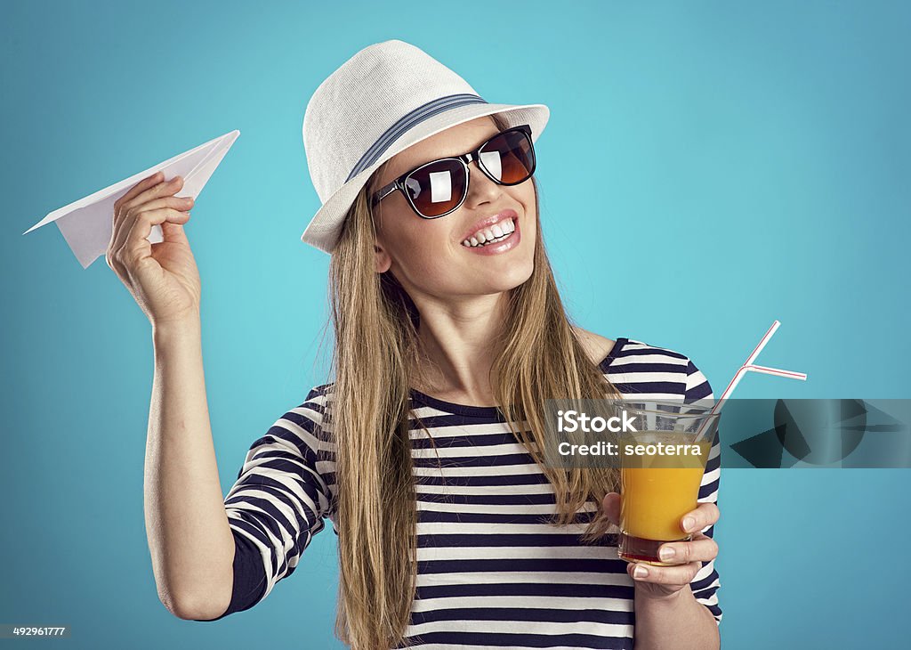 Summer girl in hat Portrait of joyful girl in sunglasses with cocktail and paper plane dreaming of summer adventure. Pretty Caucasian woman ready for refreshment. Adult Stock Photo