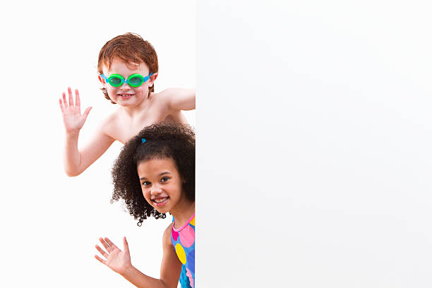 istock Children In Swimsuits Looking Around White Wall At Studio 492962265
