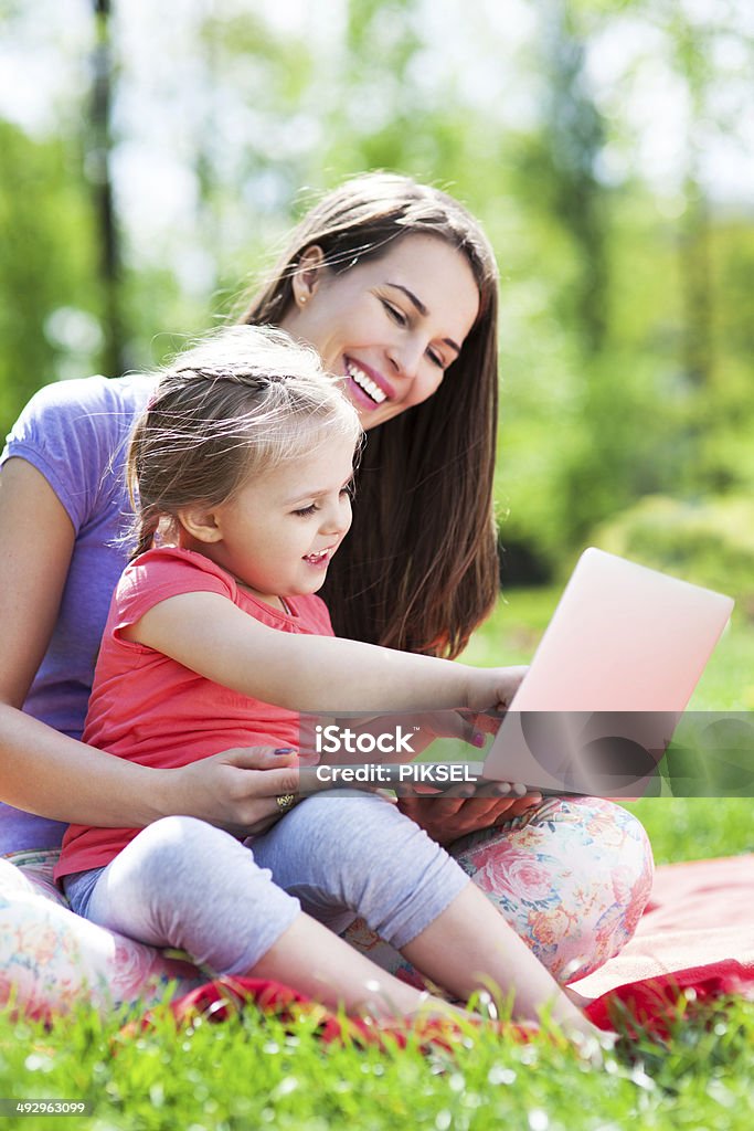 Mother and daughter using laptop outdoors Adult Stock Photo