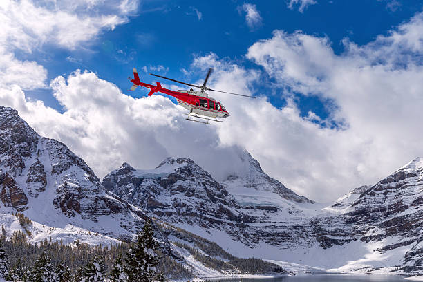 Helicopter at Assiniboine Lodge and Magog Lake Mount Assiniboine Provincial Park was established 1922. Some of the more recent history that is explorable within the park include Wheeler's Wonder Lodge (Naiset) (1924), Assiniboine Lodge (1928), the first ski lodge in the Canadian Rockies  and Sunburst (1928). Mount Assiniboine on the background. lake magog photos stock pictures, royalty-free photos & images