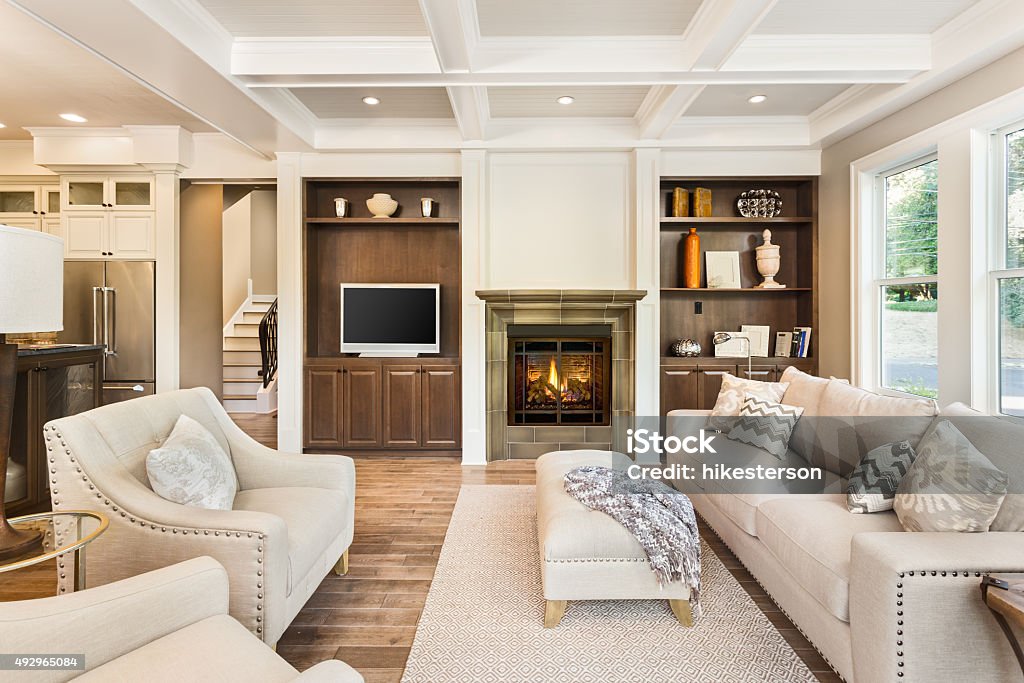 Luxurious Living Room in new home Beautiful living room with hardwood floors, coffered ceiling, and fire in fireplace in new luxury home Living Room Stock Photo