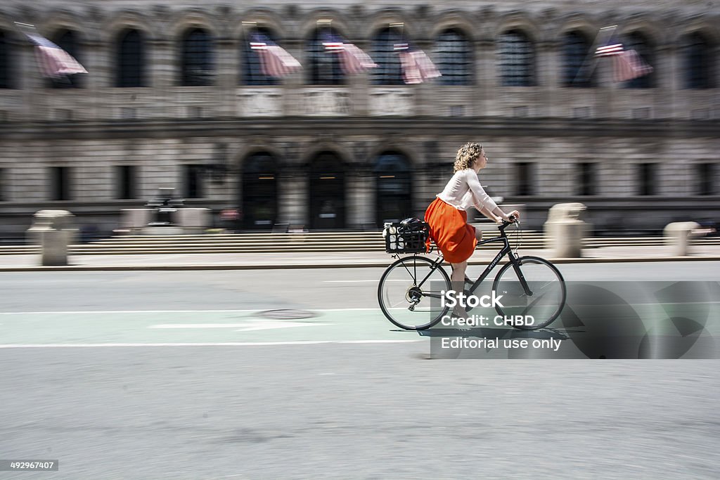 Cycling in Boston Boston, Massachusetts, USA - May 20, 2014 : young woman cycling on the streets of Boston downtown area in the front of Boston Library. Boston - Massachusetts Stock Photo