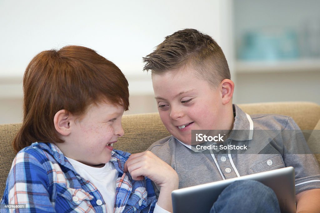 Niño con síndrome Downs y amigos jugando en tableta Digital - Foto de stock de 10-11 años libre de derechos