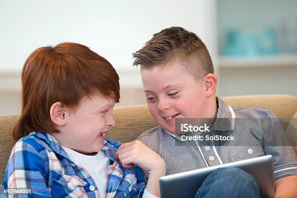 Niño Con Síndrome Downs Y Amigos Jugando En Tableta Digital Foto de stock y más banco de imágenes de 10-11 años