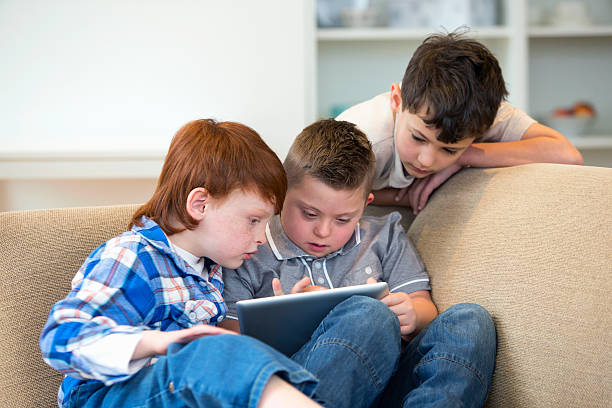 istock Boy With Downs Syndrome And Friends Using Digital Tablet 492968075