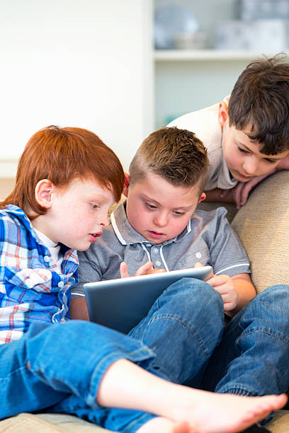 istock Boy With Downs Syndrome And Friends Using Digital Tablet 492968079