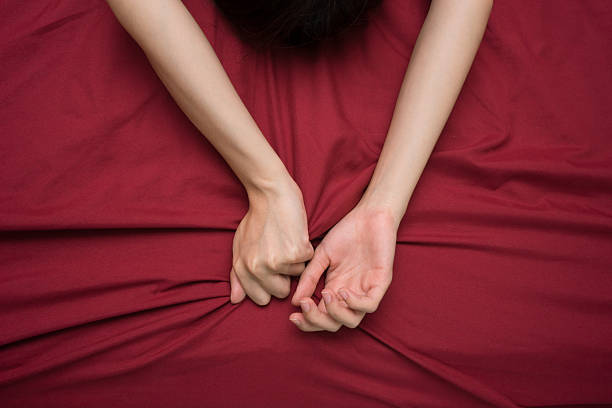 mano grasping sul letto bianca - red bed foto e immagini stock