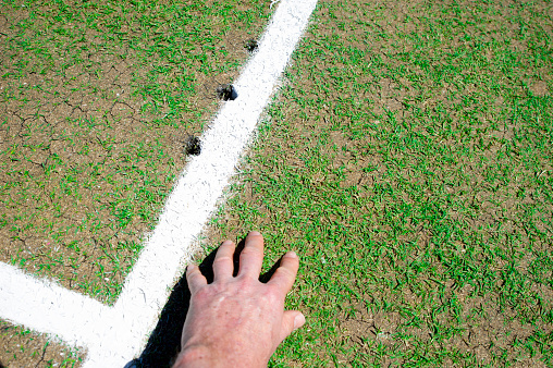 Hand checking condition of cricket pitch
