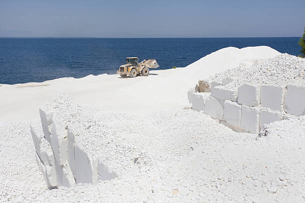 Bulldozer working at white marble quarry on Thassos in Greece, horizon at blue sea in background