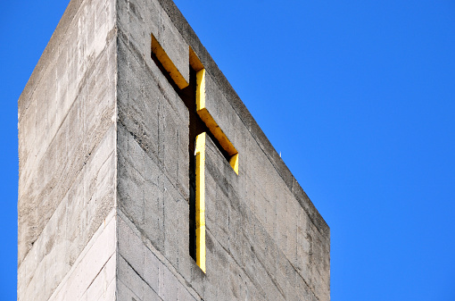 Cross on concrete wall, with blue sky and copy space