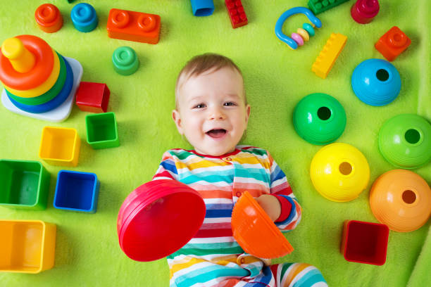 Baby boy lying on the blanket with many toys around