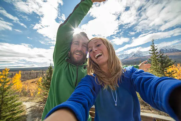 Young cheerful couple traveling in Canada takes a selfie portrait. Autumn season.