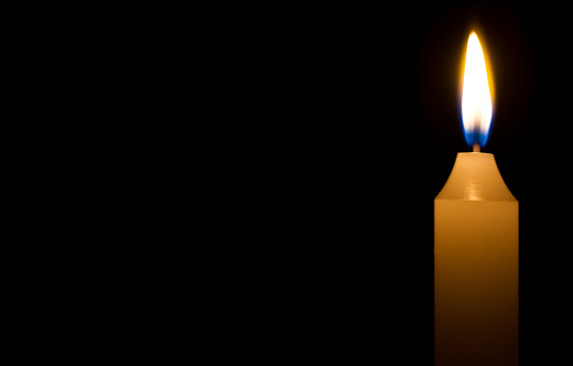 Religious concept. Burning candle on dark background