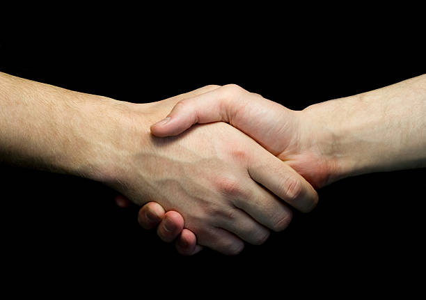 istock Two man shaking hands isolated on dark background 493027592