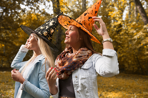 Two happy friends witches outdoor, smiling preparing for halloween party